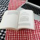 Ein aufgeschlagenes Buch auf einer Picknickdecke.